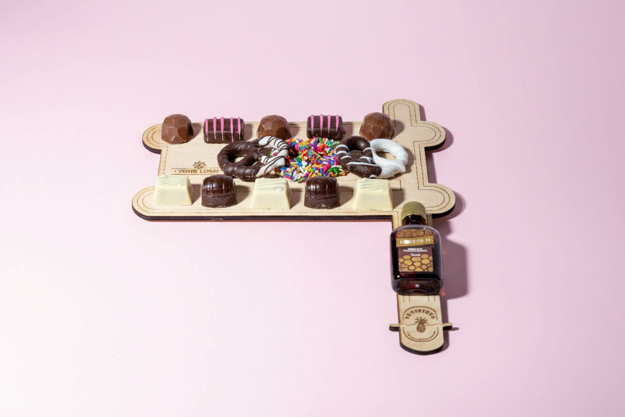 Wooden stand with various donut-shaped chocolates and a bottle of chocolate sauce on a white background