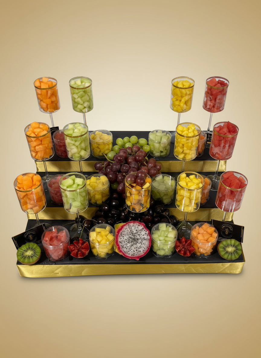 Assorted fruits in small containers on a black tray with gold rim.