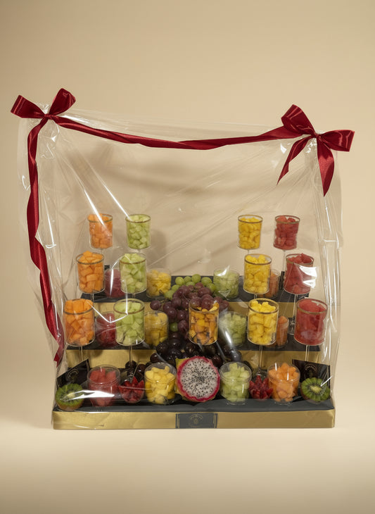 Assorted dried fruits in a clear package with a red ribbon on a white surface