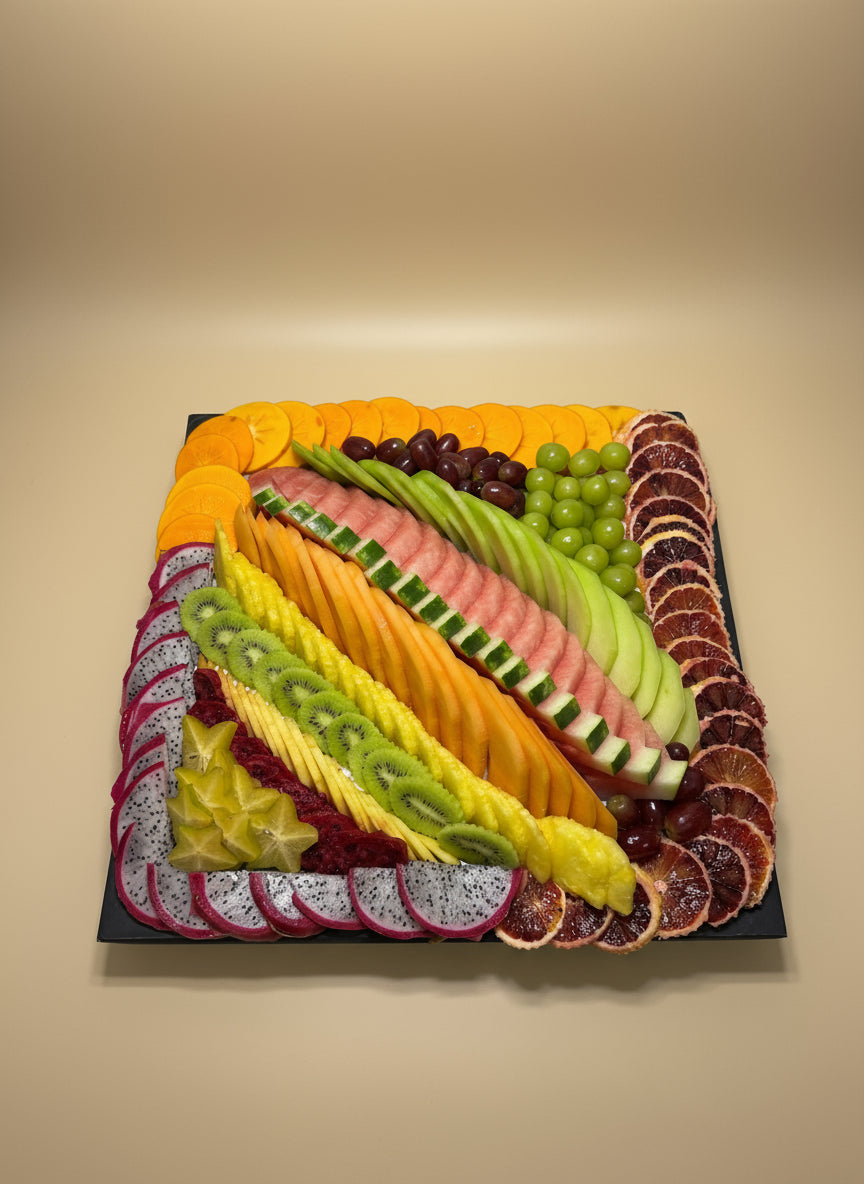 Platter of sliced fruits arranged in a decorative pattern on a white surface.